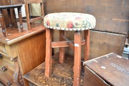 A traditional stool having upholstered seat and adzed frame