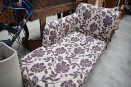 A modern chaise longue, upholstered in purple foliate patterned material.