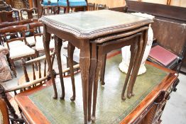 A nest of reproduction mahogany tables, with gilt tooled and glass inserts, raised on cabriole