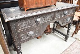 A 20th century oak desk having carved frontage with green man handles and turned supports