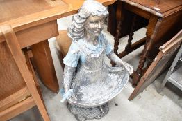 A modern cast resinous bird bath, modelled as a girl with apron outstretched, painted in blue and