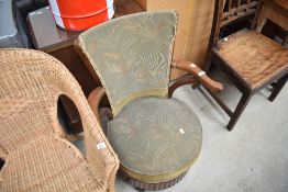 An early 20th Century golden oak sewing arm chair having storage to base, with moquette upholstery