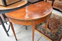 An Edwardian mahogany demi lune fold over tea table having square tapered legs, significant damage