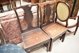 A pair of period oak vase back chairs having solid seats