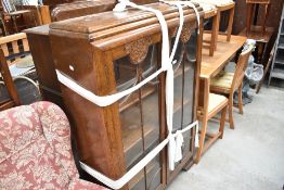 A 1930's oak display cabinet, with moulded decoration and glazed doors, on shaped bracket feet.