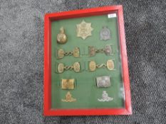 A framed and glazed collection of Artillery Helmet Plates, Cap Badges & Belt Buckles includes