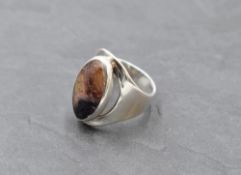 A large silver Artisan style silver ring having a Blue John panel in collared mount to open loop,