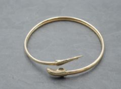 A yellow metal bangle having moulded dolphin knops, no marks tests as 9ct gold, approx 6.3g