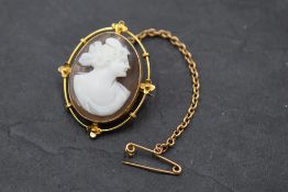 A conch shell cameo brooch depicting a maiden in profile in an open collared mount stamped 9ct