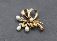 A 9ct gold brooch in the form of a tied sprig having baroque pearl and diamond chip decoration,