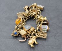 A 9ct gold charm bracelet with padlock clasp and twenty five yellow metal/gold charms including
