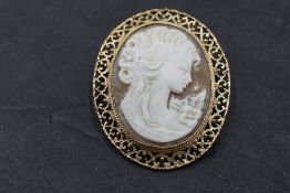 A conch shell cameo brooch depicting a maiden in profile within a decorative 9ct rose gold mount,