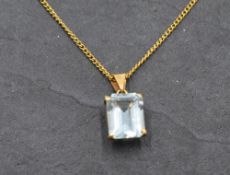 An aquamarine style pendant in a yellow metal mount on a yellow metal chain stamped 18K, approx