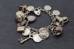 A white metal charm bracelet with padlock clasp stamped silver having 10 three penny coins and eight