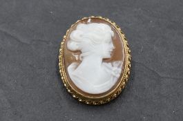 A conch shell cameo brooch depicting a maiden in profile having decorative 9ct gold mount