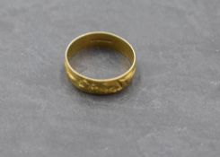 An 18ct gold wedding band having engraved floral and foliate decoration, size T/U & approx 3.1g