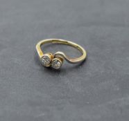 A two stone diamond ring, total approx 0.15ct in collared mounts to crossover shoulders on a