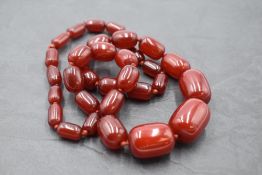 A string of graduated cherry amber cylindrical beads, approx 24' & 68.5g