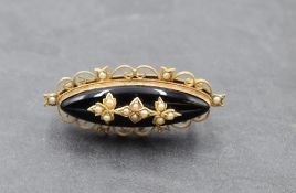 A Victorian black onyx oval mourning brooch having seed pearl decoration in a yellow metal