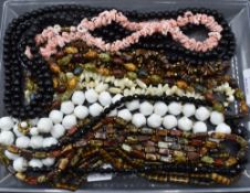 A selection of strings of beads including coloured shell, mother of pearl, glass, polished stone