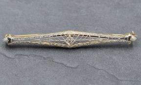 An Art Deco style yellow metal bar brooch stamped 14K having a central diamond in an open mount,