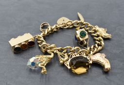 A 9ct gold charm bracelet with padlock clasp and eight 9ct gold charms including traffic lights,