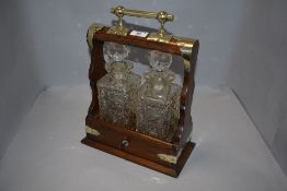 An Edwardian oak and brass tantalus having cut glass decanters with HM silver name badges for Whisky