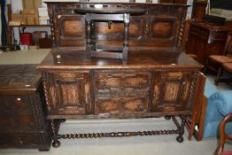 A 20th century oak side board with supported back and cushioned drawers with twist rails