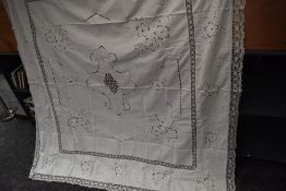 An antique white work linen bed throw with deep crotchet edging and cut work floral pattern.