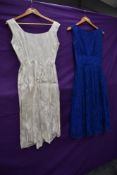Two 1950s dresses, one blue lace with gathered waist detail,the other of white brocade.