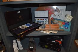A selection of art materials including watercolour paint, coloured pencils and more.