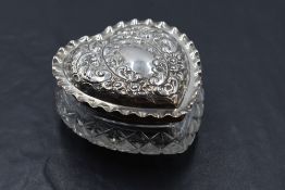 An Edwardian silver lidded cut glass heart shaped dressing table jar, the silver lid with crimped