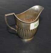 An Edwardian silver cream jug< of helmet form with half fluted body and angular handle, marks for