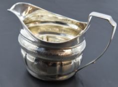 A George III silver cream jug, of helmet form with reeded rim and moulded body with bands of