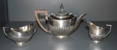 An Edwardian silver three-piece teaset, comprising teapot, sugar and cream, of oval half fluted