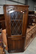 A mid to late 20th century oak linen fold corner cupboard, in the Priory style