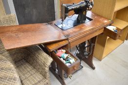 A traditional oak cased singer sewing machine on treadle base, with electrical conversion