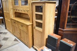 A natural pine narrow cabinet with three glazed panels to door