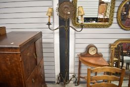 A 1930's arts and crafts inspired combined standard lamp and clock, having bronzed brass twisted and