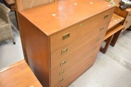 A vintage teak laminate on chipboard chest of six long drawers, having brass campaign handles