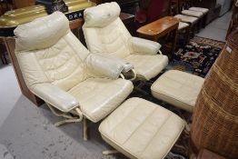 A pair of vintage cream leather recliner chairs and footstools on metal frames