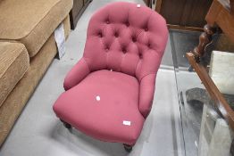 A Victorian button back nursing chair having burgundy upholstery and turned legs