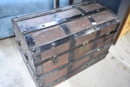 A traditional dome topped travel trunk with wooden bindings, metal edges and canvas leather work