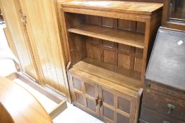 An Arts and Crafts low bookcase , with cupboard base, of typical Robert Thompson design. The