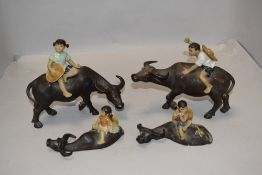 A group of four 20th century Chinese pottery figures, Children on oxen in various poses.