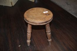 A vintage wooden milking stool of small proportions.