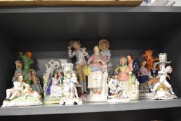 A selection of bisque and Staffordshire figures including boy sat with dog and cherub candle stick