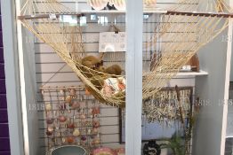 A hammock having wooden batons to ends and a shell wall hanging.
