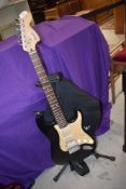 A Squier by Fender Stratocaster electric guitar, with fender gig bag and stand