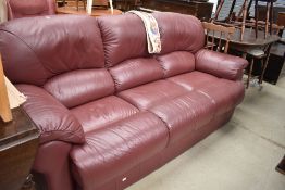 A modern three seater settee in soft burgundy leather
